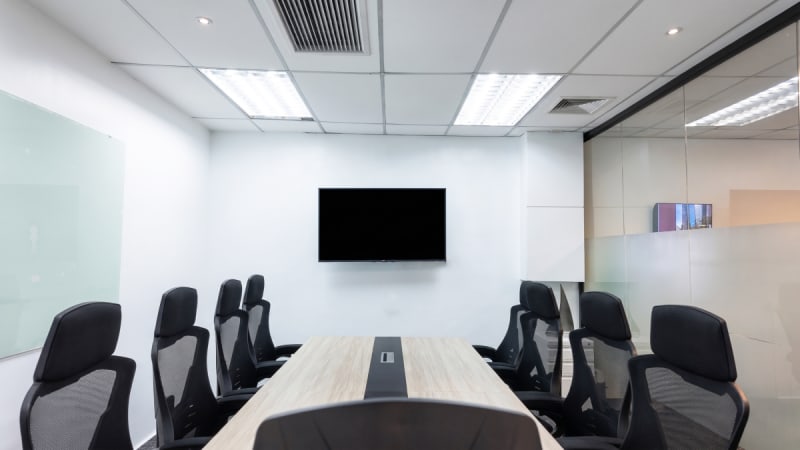 Modern conference room with sleek chairs, large screen, and glass walls. Ideal for meetings.