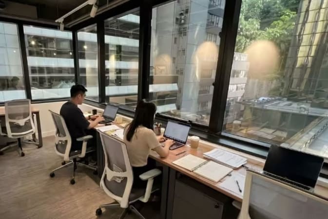 Bright, open coworking space with modern desks and expansive city views on Duddell Street.