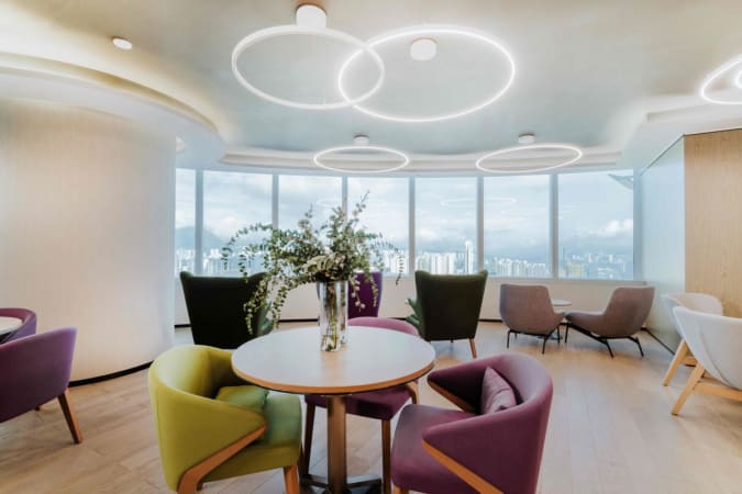 Bright coworking space with modern seating, circular lighting, and stunning city views in Kowloon.
