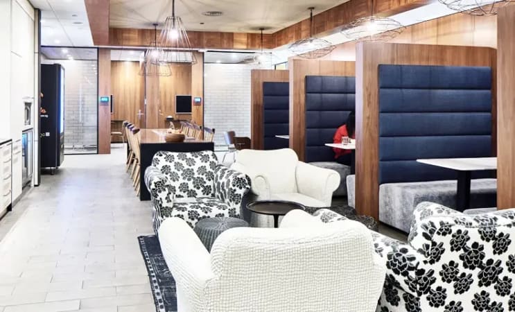 Elegant coworking space with plush armchairs, private booths, and modern lighting in Marina Boulevard.