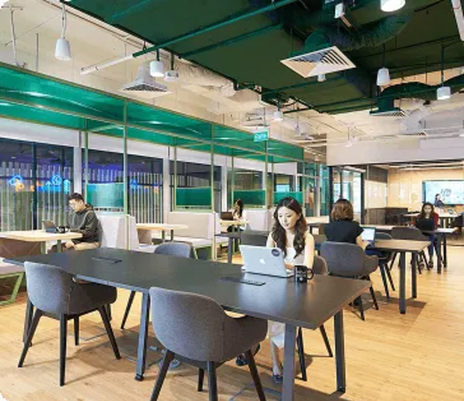 Modern coworking space with open seating, vibrant decor, and ample natural light.