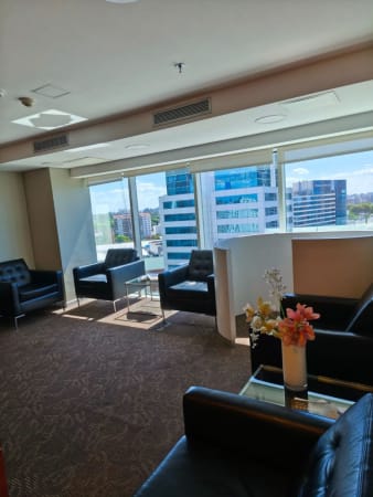 Modern coworking lounge with natural light, city views, and comfortable seating.
