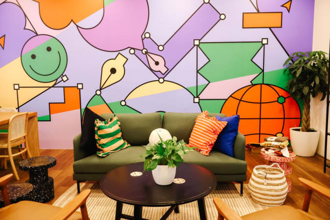 Vibrant coworking space with colorful mural, cozy seating, and lively decor on Neil Road.