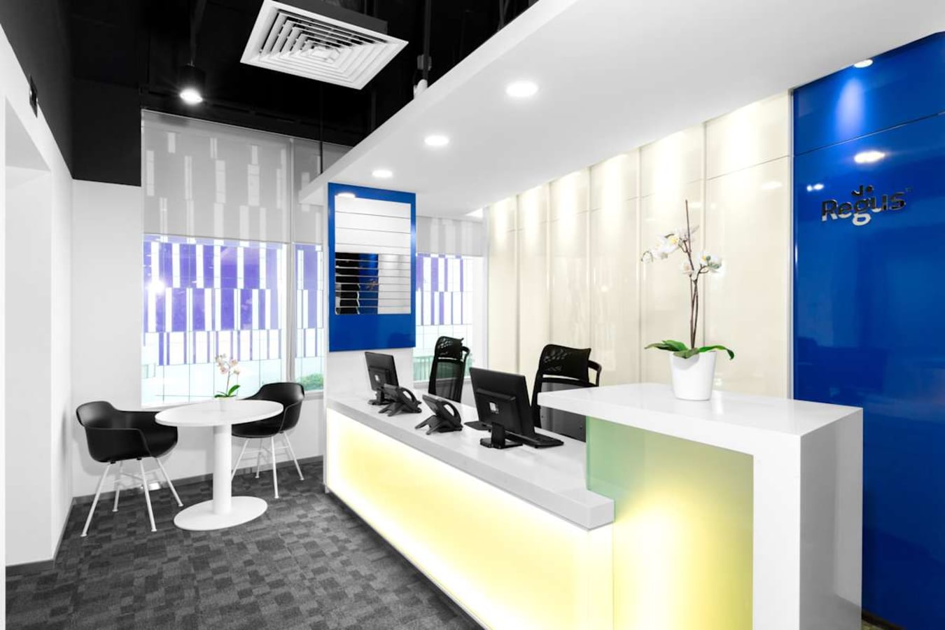 Modern coworking space with sleek reception, vibrant accents, and collaborative seating area.