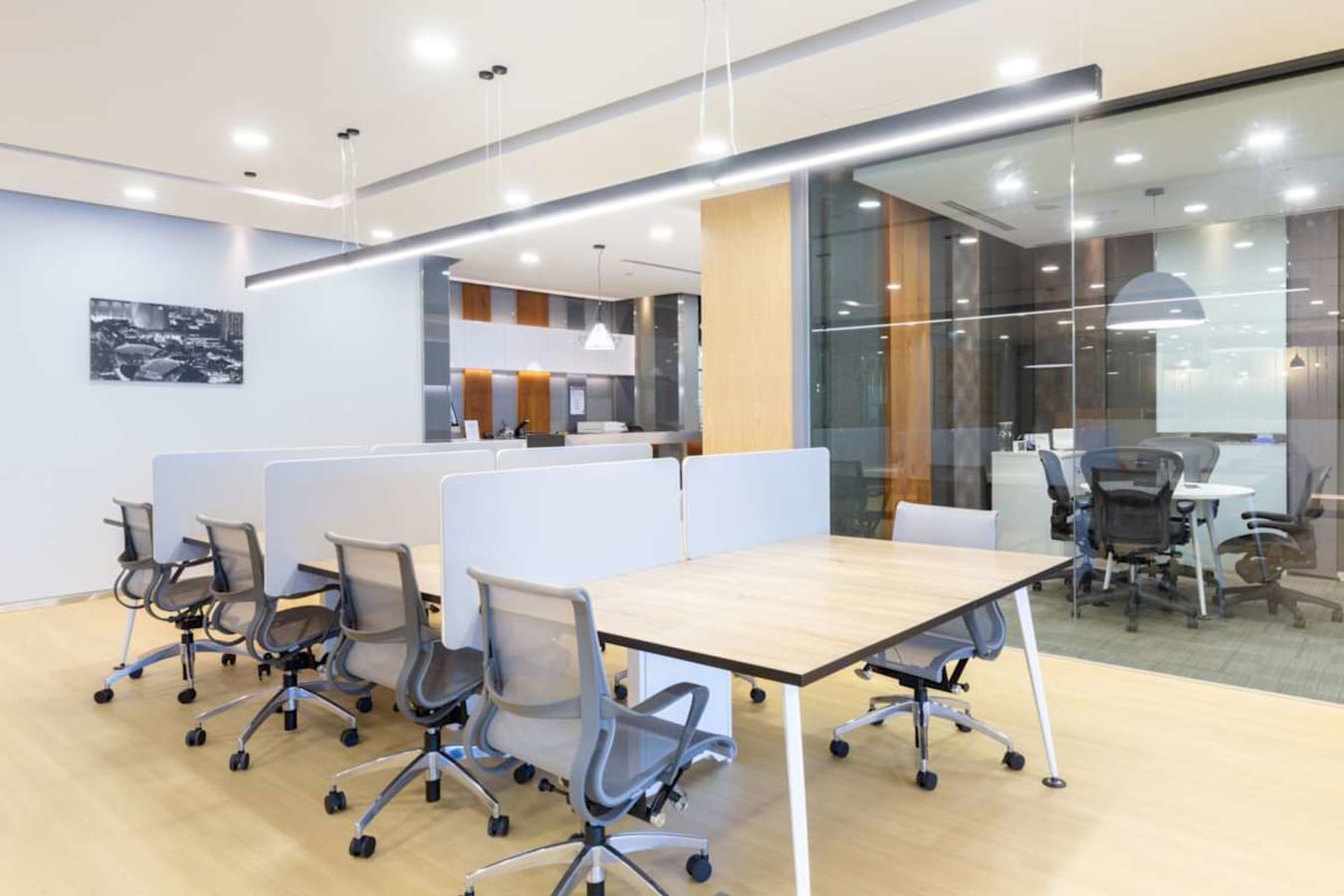 Modern coworking space with ergonomic chairs, spacious desks, and sleek glass-enclosed meeting room.
