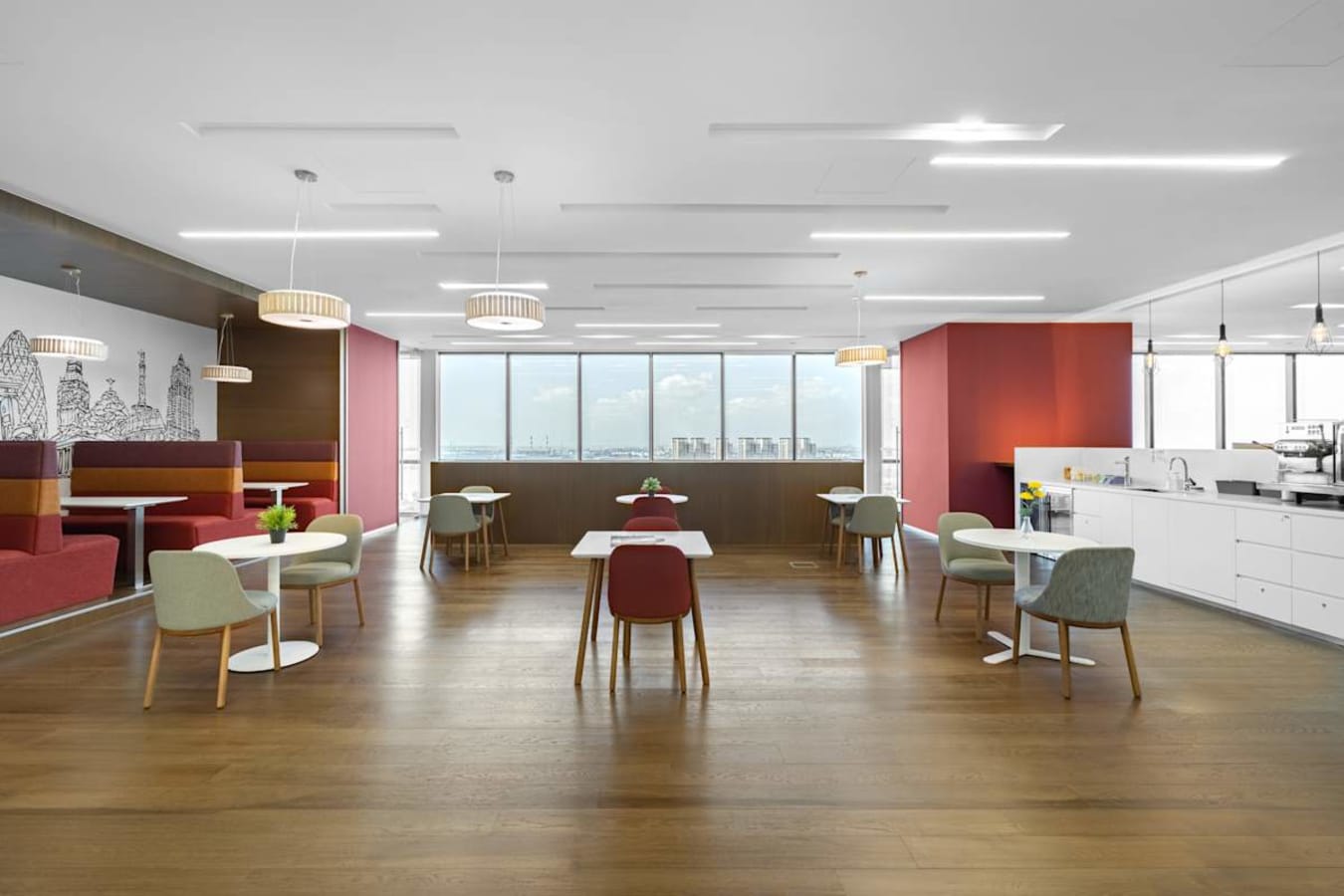 Bright coworking space with modern seating, ample natural light, and kitchen amenities.