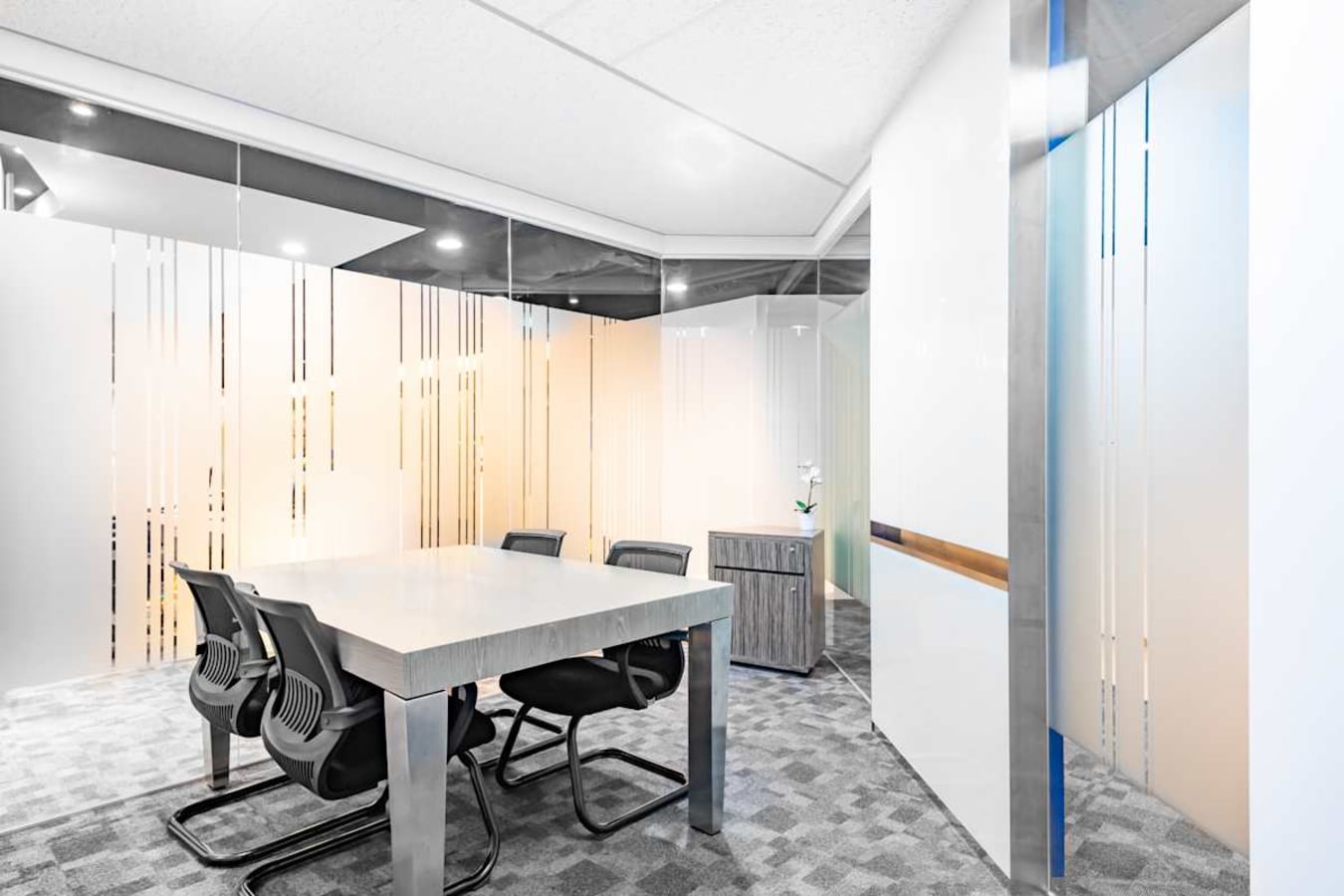 Modern meeting room with sleek table, ergonomic chairs, and frosted glass panels in a flexible workspace.