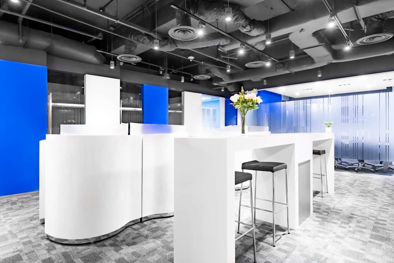 Modern coworking space on Thomson Road featuring sleek white furnishings and vibrant blue accents.