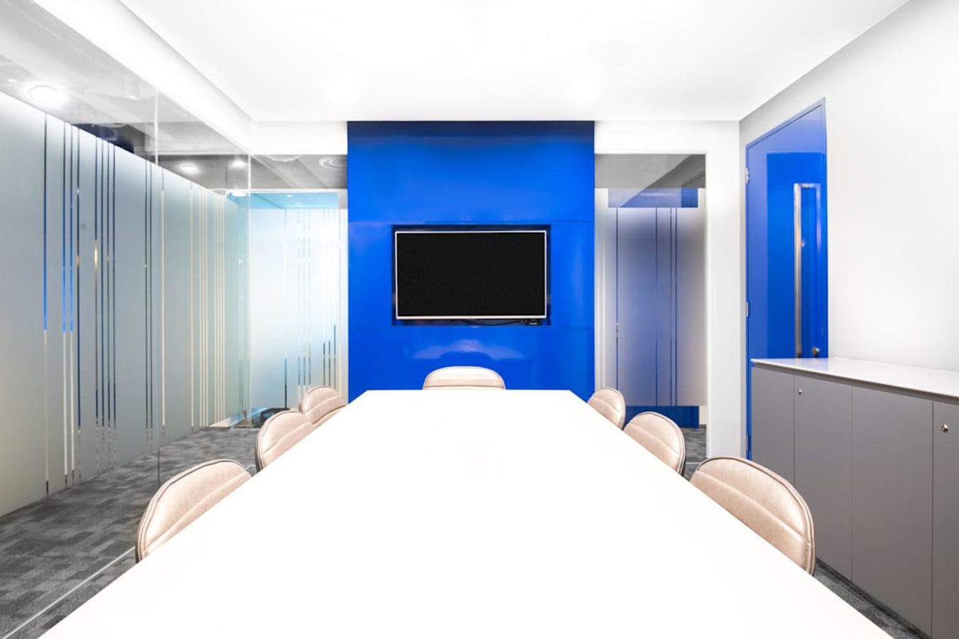 Modern meeting room with sleek blue accents, glass partitions, and conference-ready technology.
