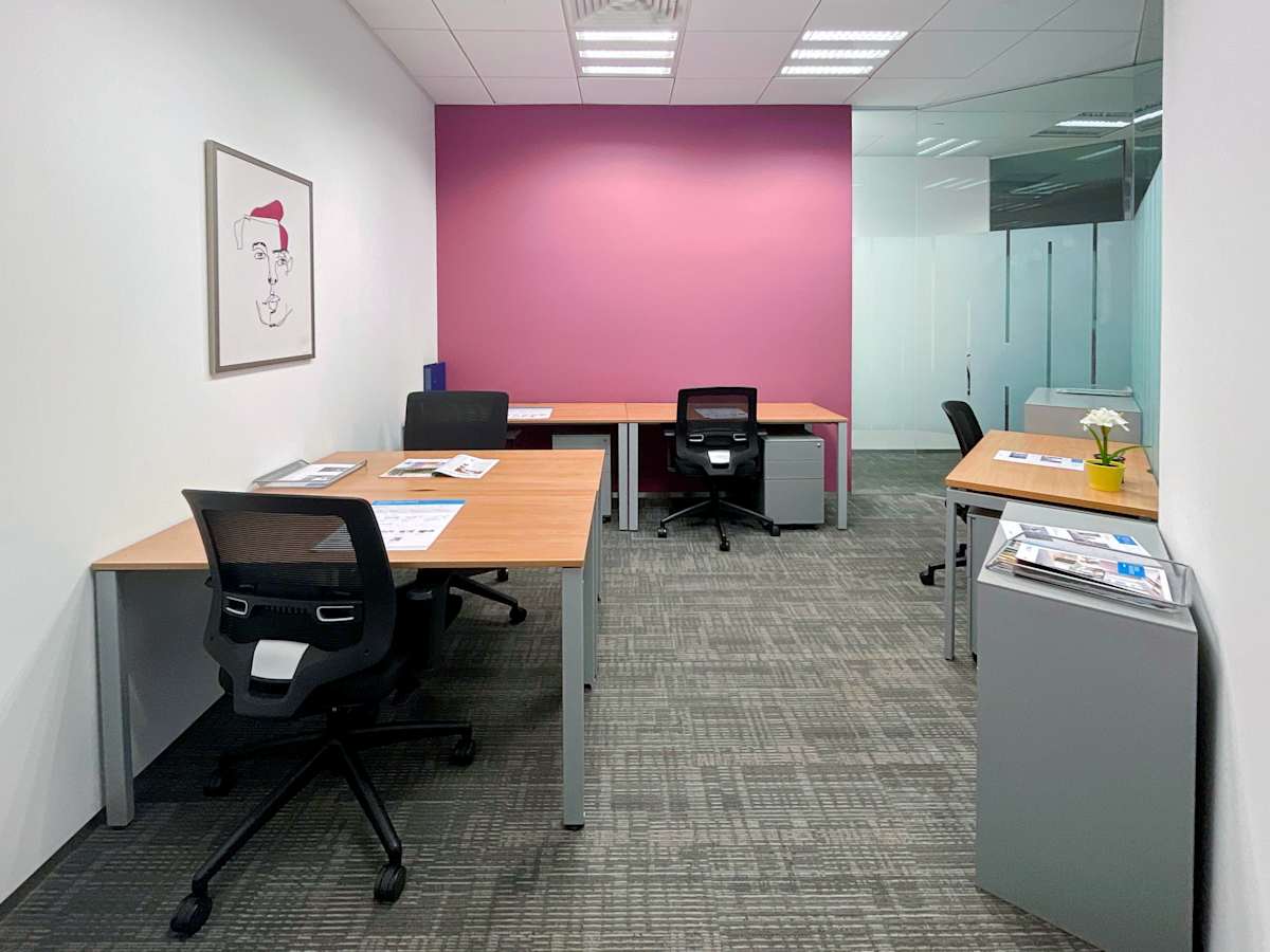 Bright coworking space with modern desks, ergonomic chairs, and vibrant accent wall.