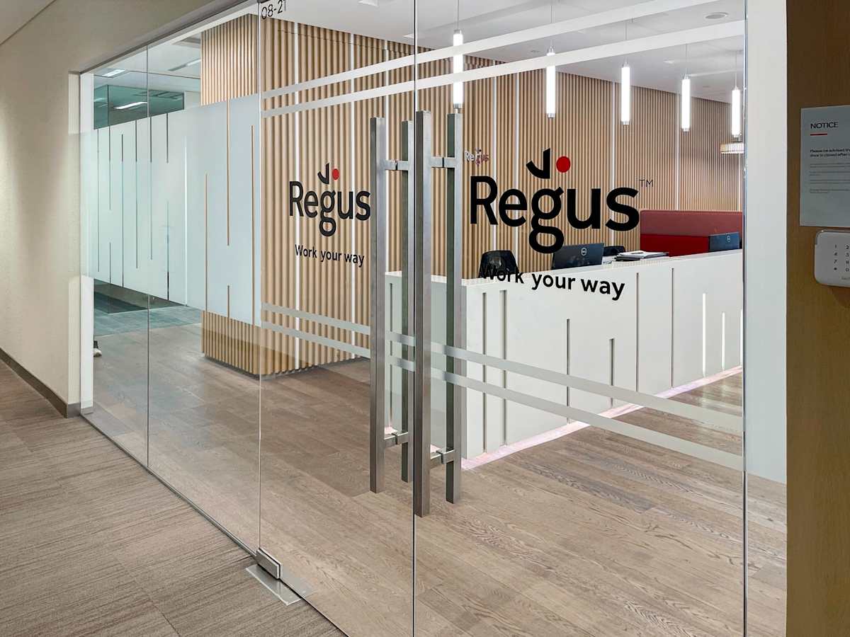 Modern coworking space with sleek glass entry, warm wooden accents, and inviting reception.
