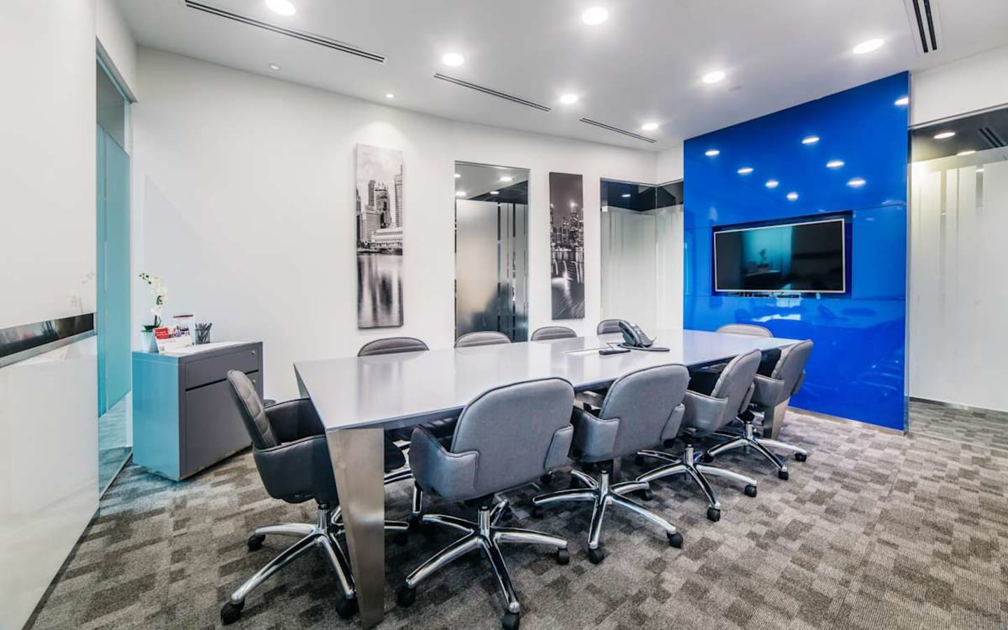 Modern meeting room with sleek furnishings and a vibrant blue accent wall, perfect for collaboration.