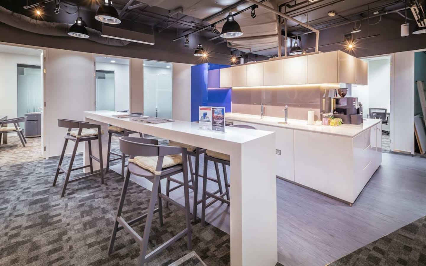 Modern coworking area with a sleek kitchenette and communal high-top tables in Changi Business Park.