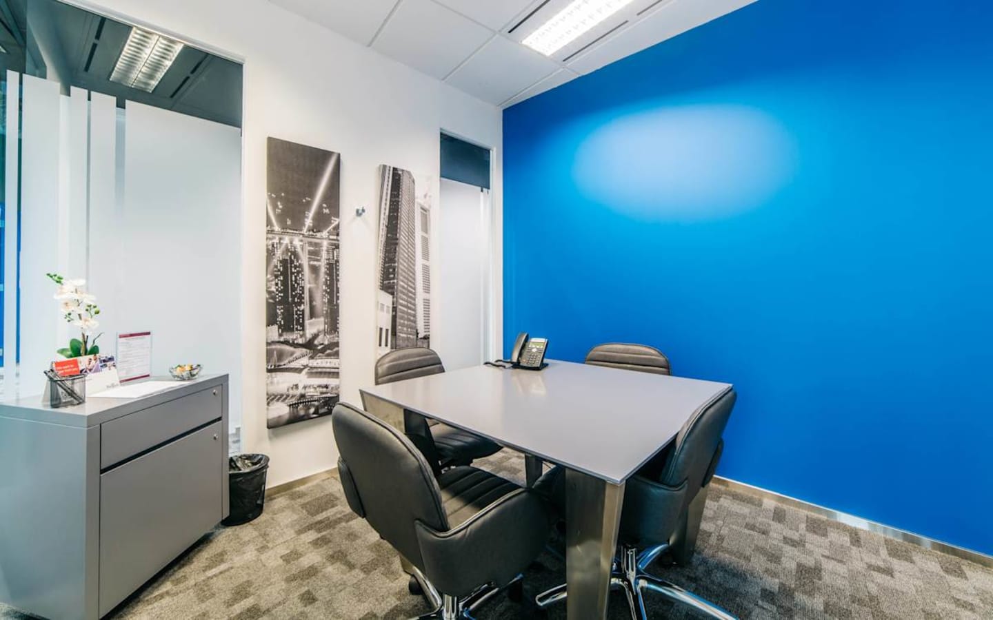 Modern coworking space with vibrant blue accent wall and sleek furnishings in Changi Business Park.