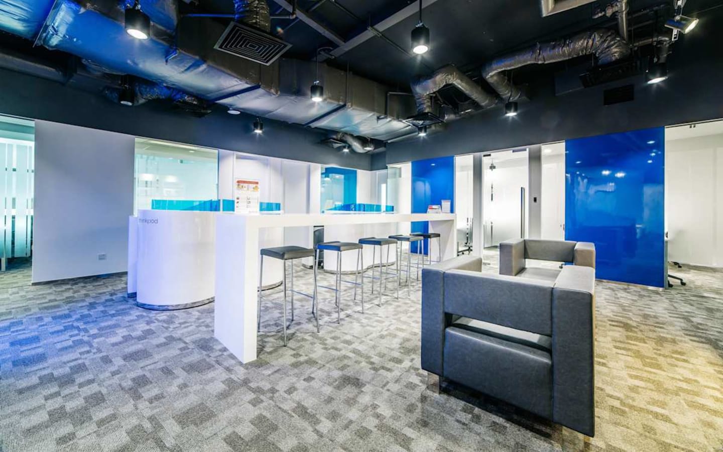 Modern coworking space with vibrant blue accents, open seating, and ample natural light.