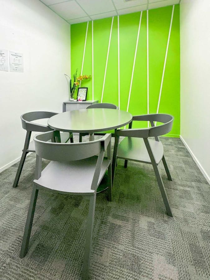 Modern meeting room with sleek furniture and vibrant green accent wall in a flexible coworking space.