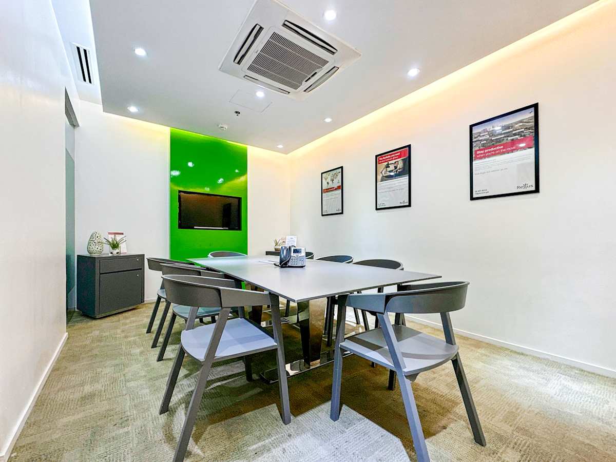 Modern coworking space with a sleek conference room, vibrant green accents, and ample seating.