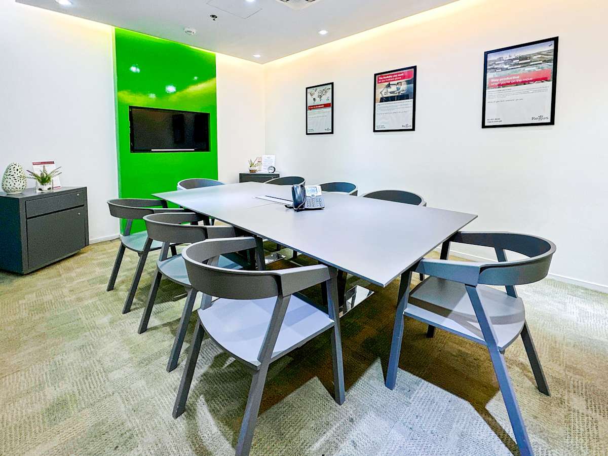 Modern conference room with sleek table, ergonomic chairs, and vibrant green accent wall.