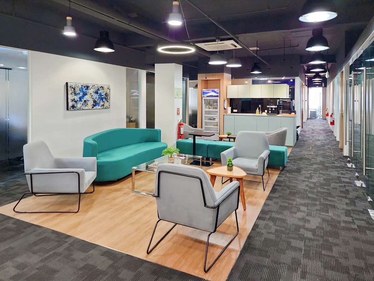 Modern coworking space with cozy seating, bright lighting, and a kitchenette on Jose Abad Santos Ave.