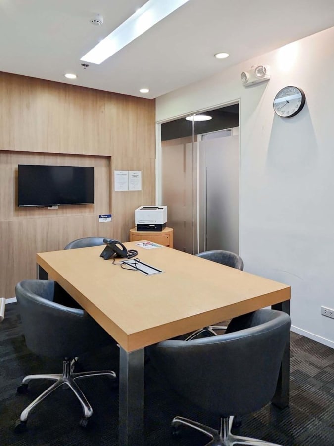 Modern meeting room with sleek table, plush chairs, TV, and printer. Ideal for teamwork.