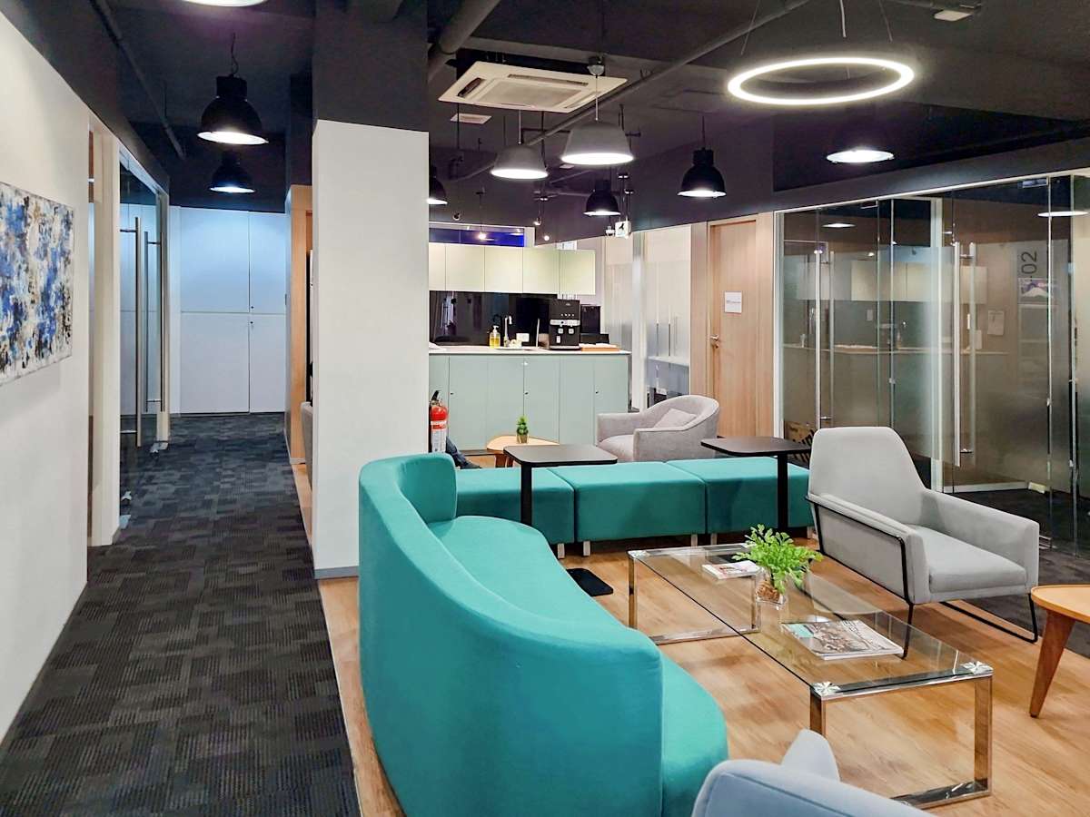 Modern coworking space with stylish seating, natural light, and sleek glass-walled meeting rooms.