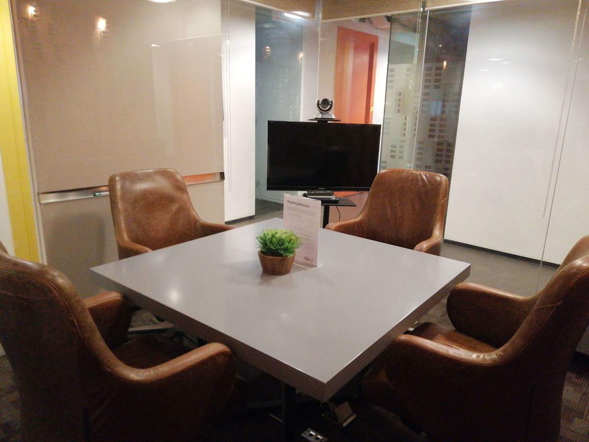 Sleek meeting room with a modern table, leather chairs, and video conferencing setup. Ideal for collaboration.