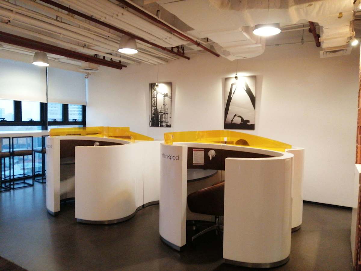 Modern coworking space with cozy pods, natural light, and industrial-style decor.
