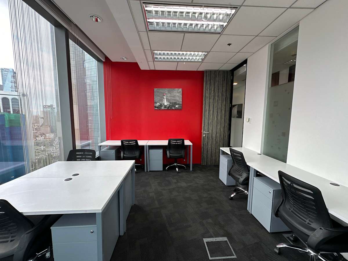 Modern office with bright red accent wall, sleek desks, and ergonomic chairs.