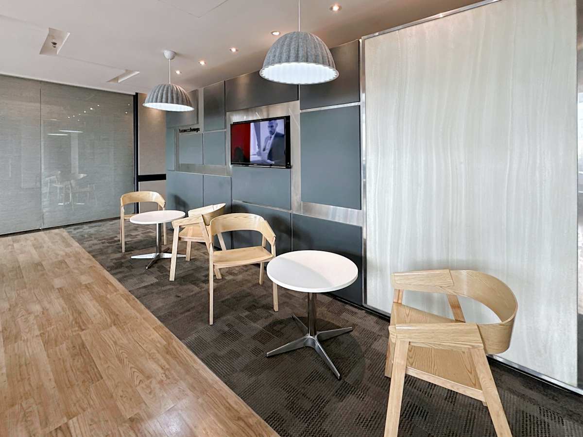 Modern coworking area with stylish seating, soft lighting, and a sleek media wall.