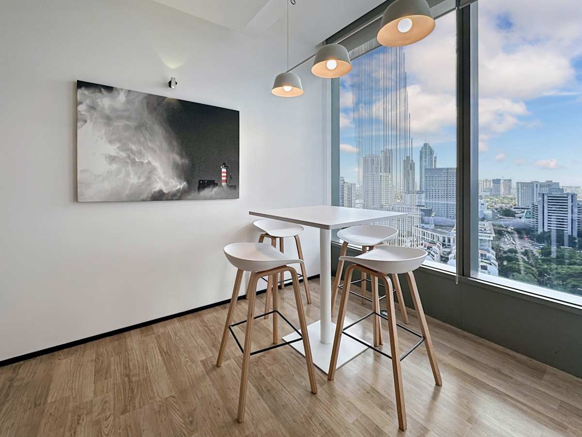 Modern coworking space with city views, sleek high table, and stylish pendant lighting.