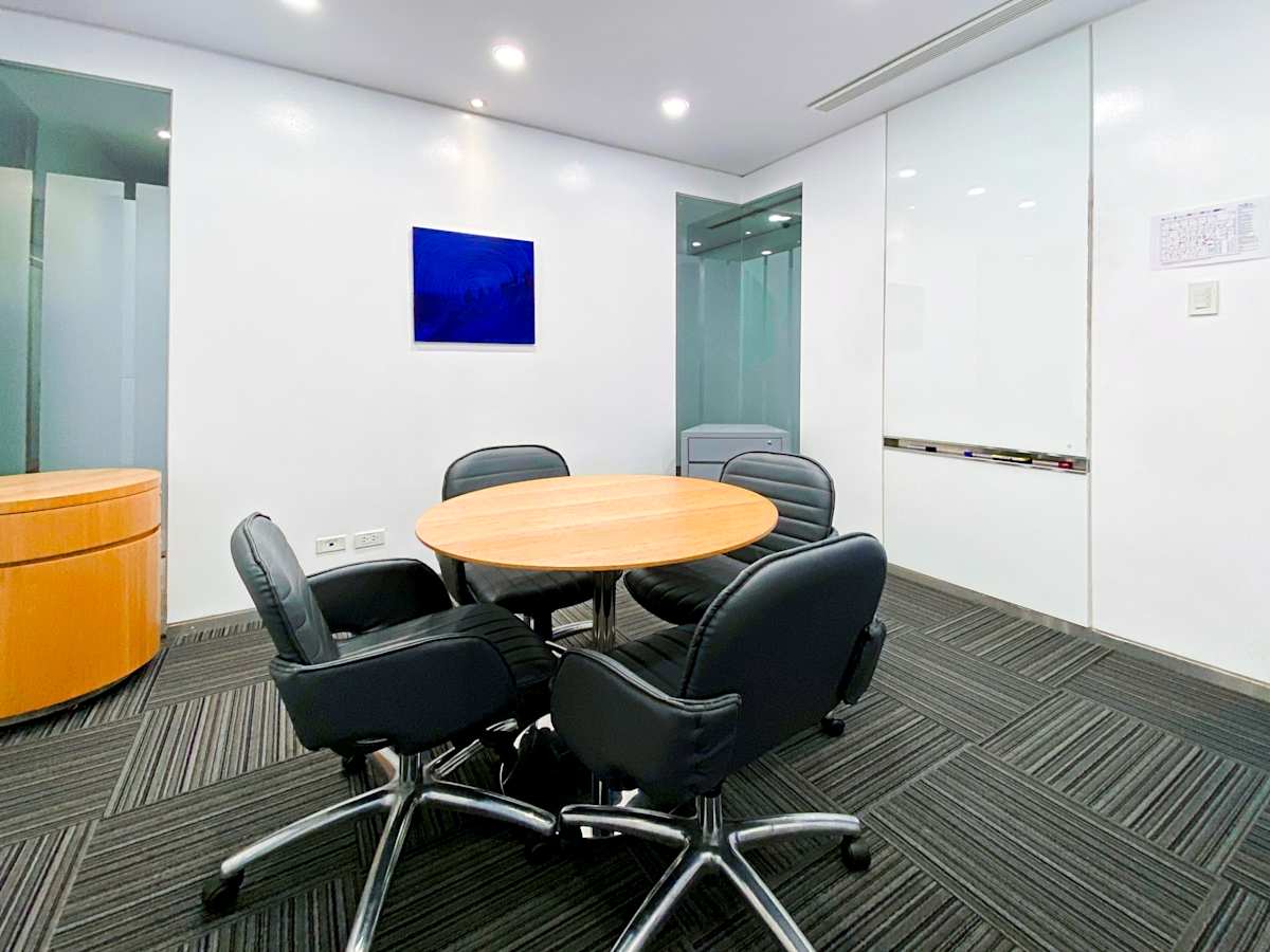 Modern meeting area with comfortable seating and round table, enhanced by bright lighting.