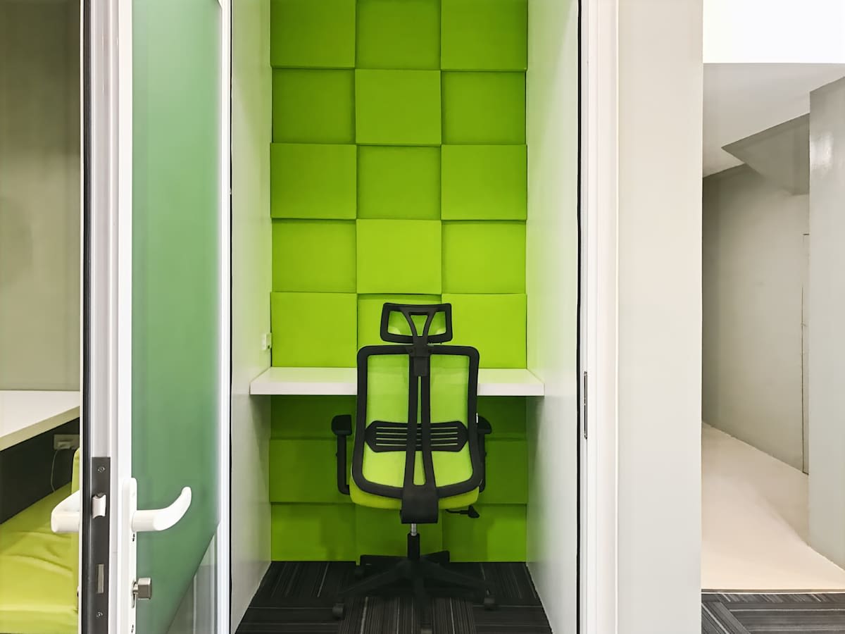 Compact private workspace with vibrant green accents and ergonomic chair. Perfect for focused work.