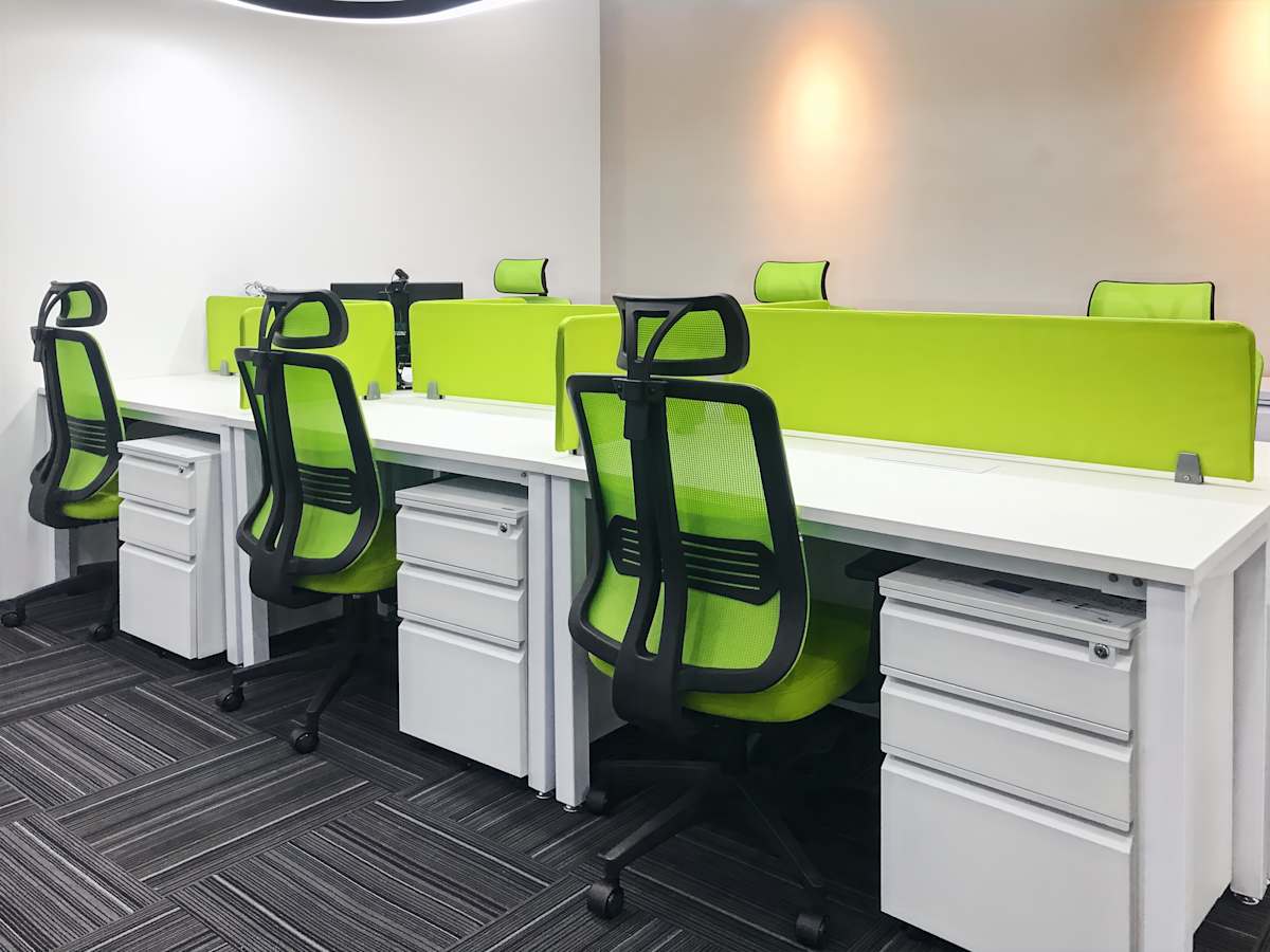 Modern office space with vibrant green chairs, sleek desks, and ample storage solutions.