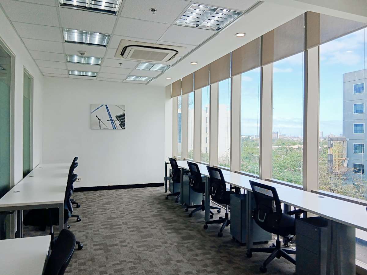 Bright workspace with large windows, modern desks, and ergonomic chairs. Ideal for productivity.