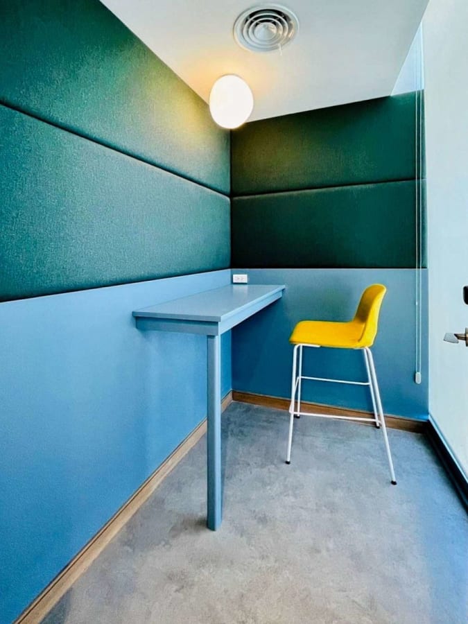 Compact workspace with vibrant accents, featuring a standing desk and modern seating.