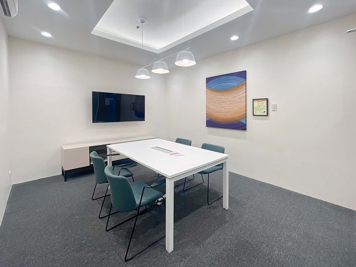 Modern meeting room with sleek table, comfortable seating, and wall-mounted TV.