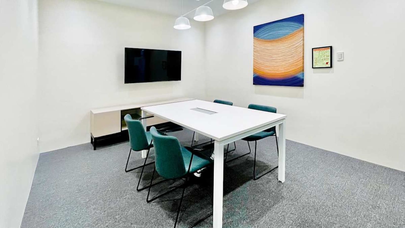 Modern meeting room with a sleek table, comfortable chairs, and vibrant artwork. Ideal for collaboration.