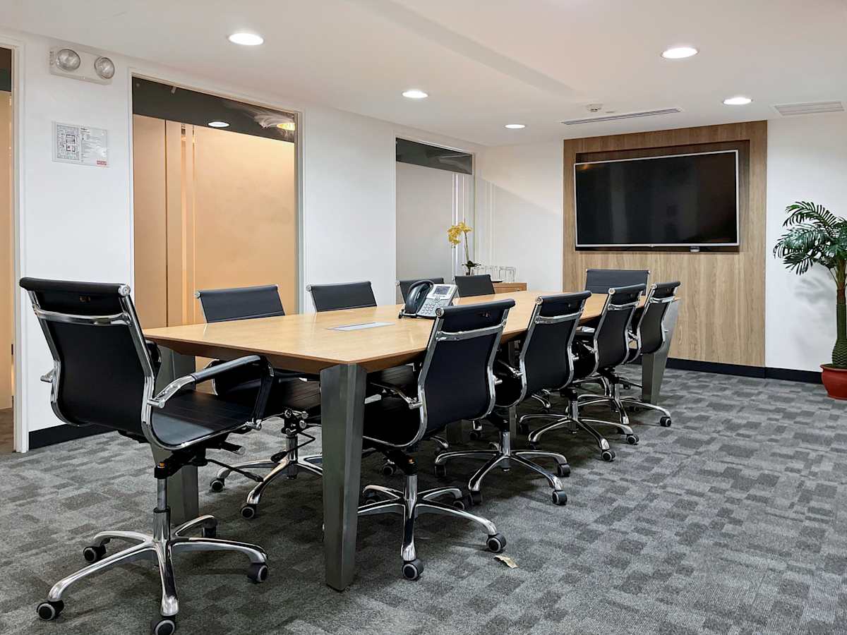 Modern conference room with ergonomic chairs, sleek table, and large screen for presentations.