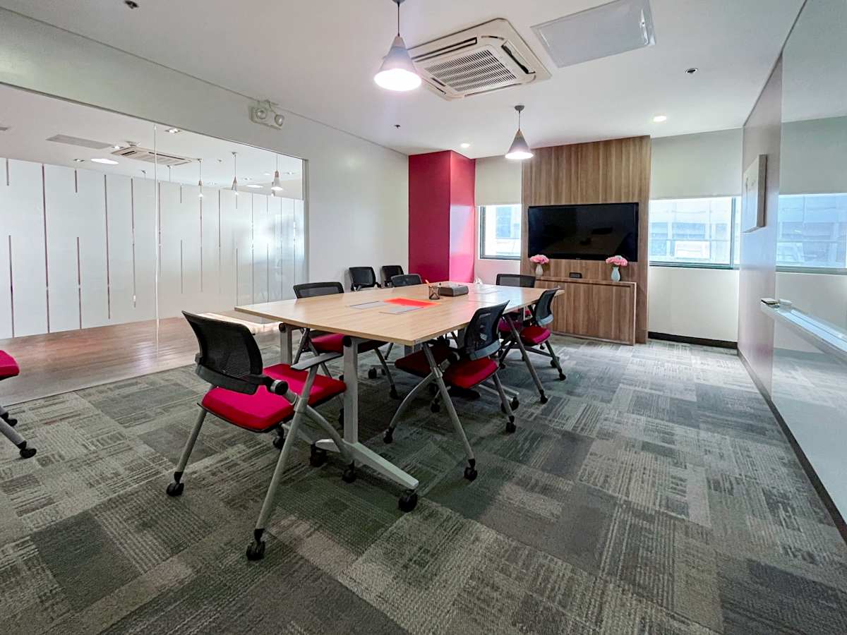 Modern meeting room with ample natural light, stylish chairs, and a large screen for presentations.