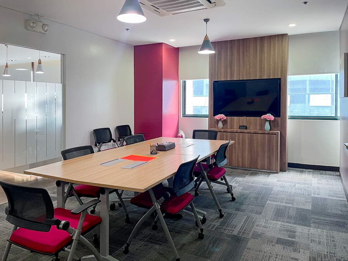 Modern conference room with sleek wooden table, ergonomic chairs, and large screen presentation setup.