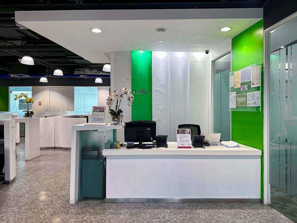 Modern reception area with sleek desk, vibrant green accent wall, and ample lighting.