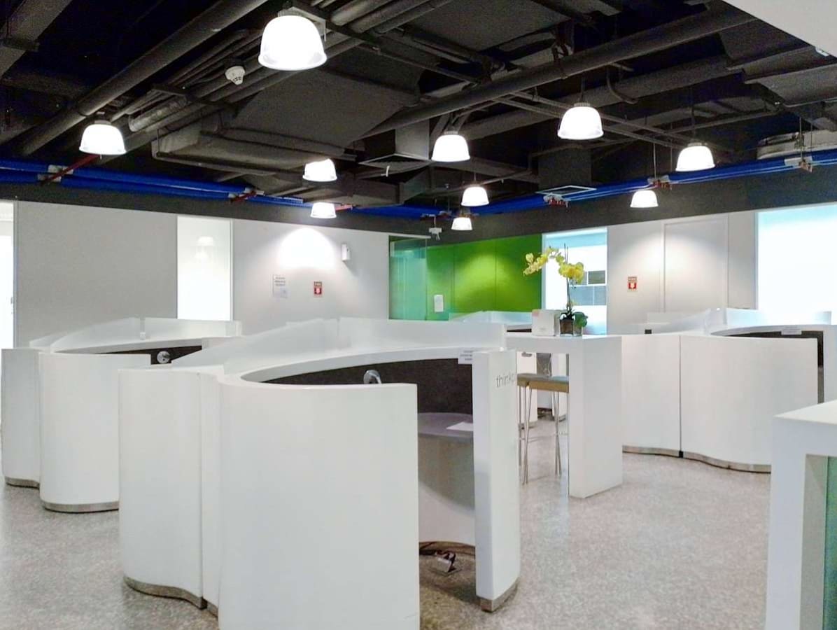 Modern coworking space with sleek white cubicles and vibrant accent wall. Ample lighting enhances productivity.