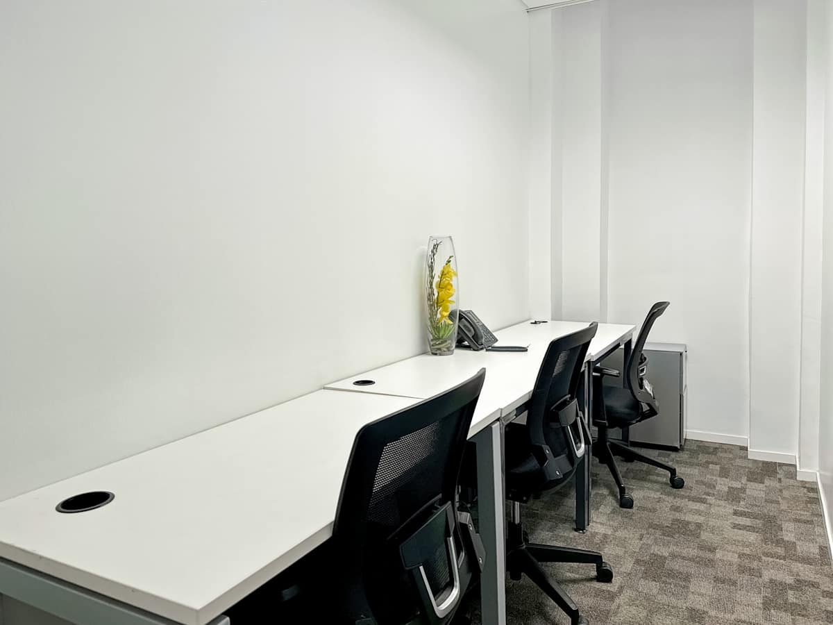 Bright, minimalistic workspace with ergonomic chairs and clean white desks in a quiet setting.