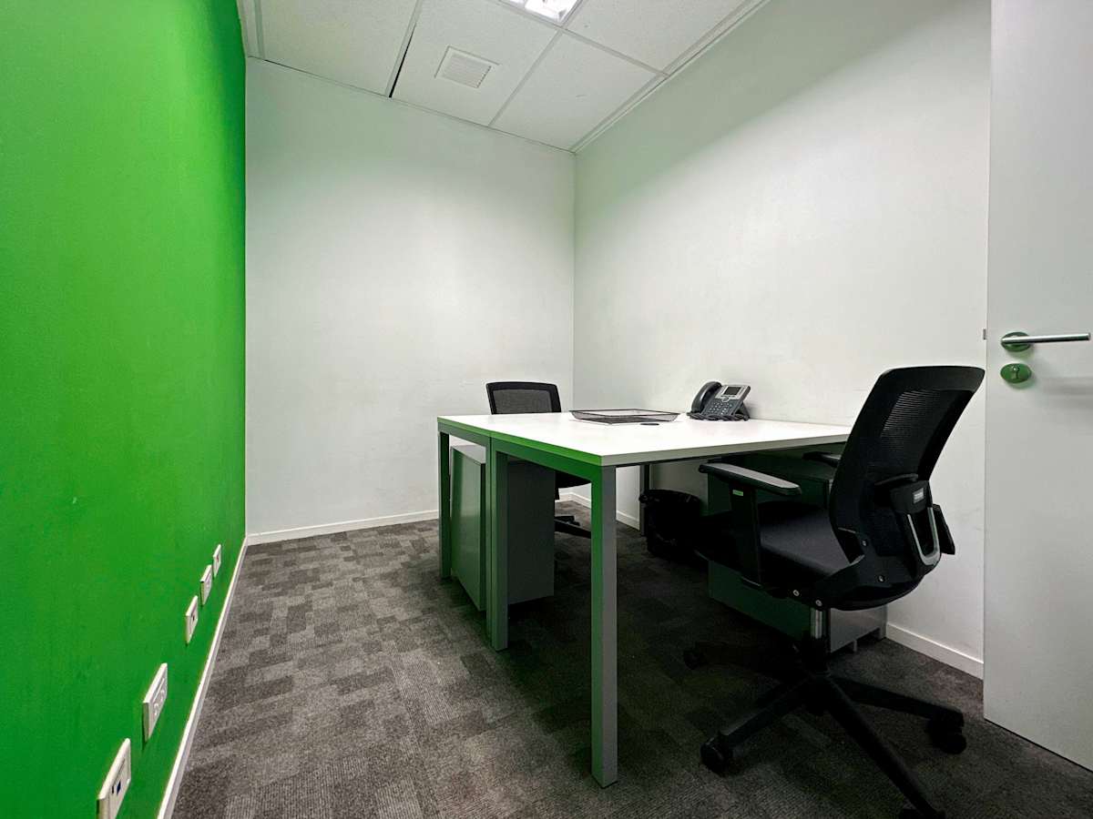 Modern office with vibrant green accent wall, sleek desks, and ergonomic chairs. Ideal for productivity.