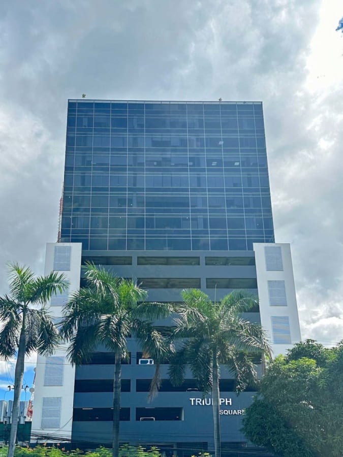 Modern office building with sleek glass facade and palm-lined entrance. Perfect for dynamic businesses.