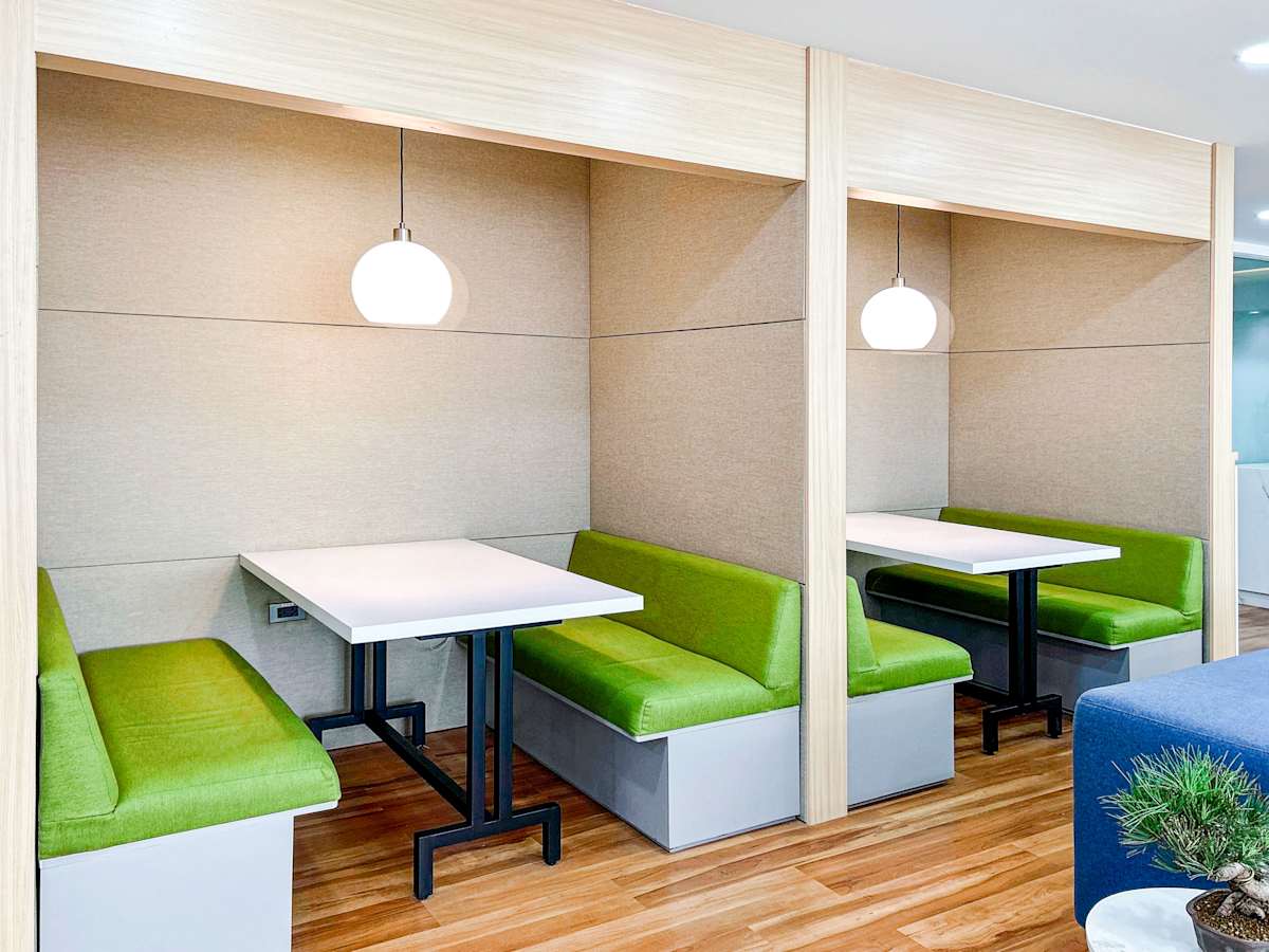 Modern coworking space with cozy booths and vibrant green seating for collaboration.