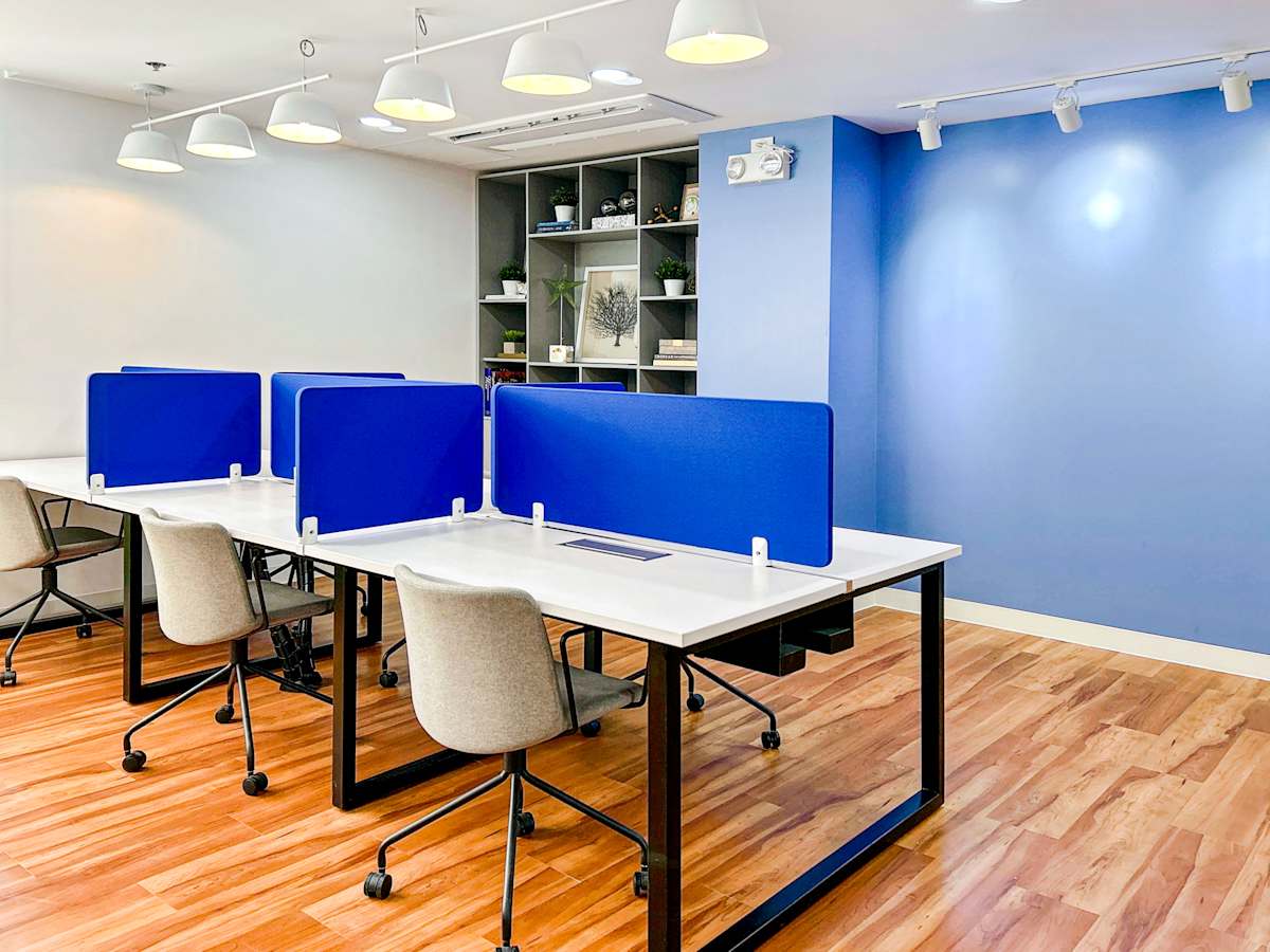 Modern office space with blue dividers, sleek desks, and ample lighting. Ideal for productivity.