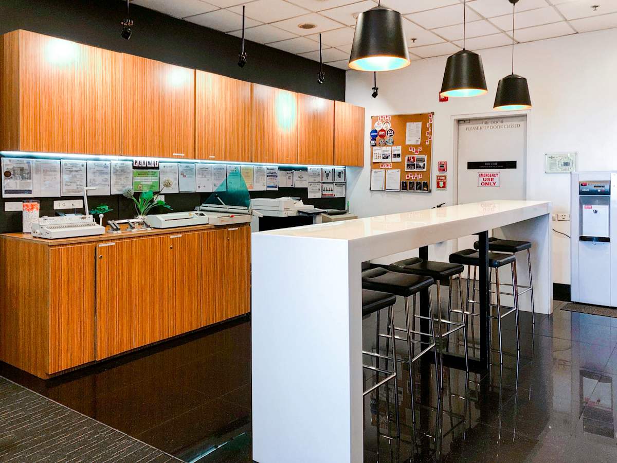 Modern office space with high-top seating, sleek wooden cabinetry, and ample lighting. Perfect for collaboration.