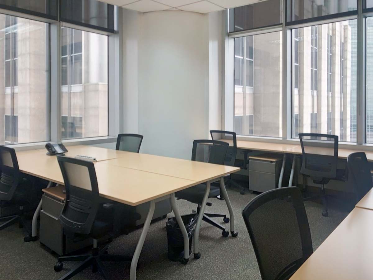 Modern office with large windows, ergonomic chairs, and ample desk space. Ideal for productivity.