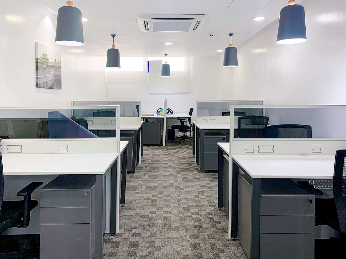 Modern coworking space with sleek desks, ample lighting, and a clean, professional ambiance.